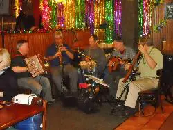 A band of five men sitting on chair and playing music