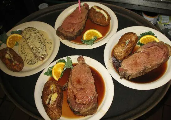 Four plates with meat and lemon on the table